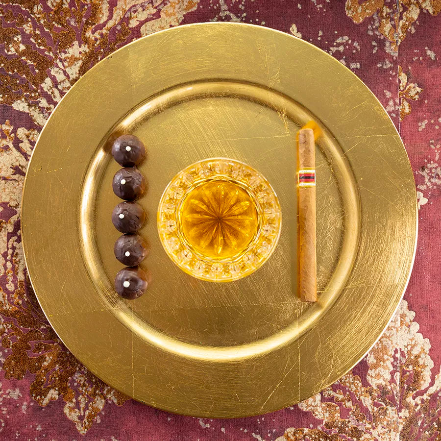 DORNAUERS Grand Cru Pralinen Rum auf einem goldenem Teller, daneben eine Zigarre und ein Rum Glas 