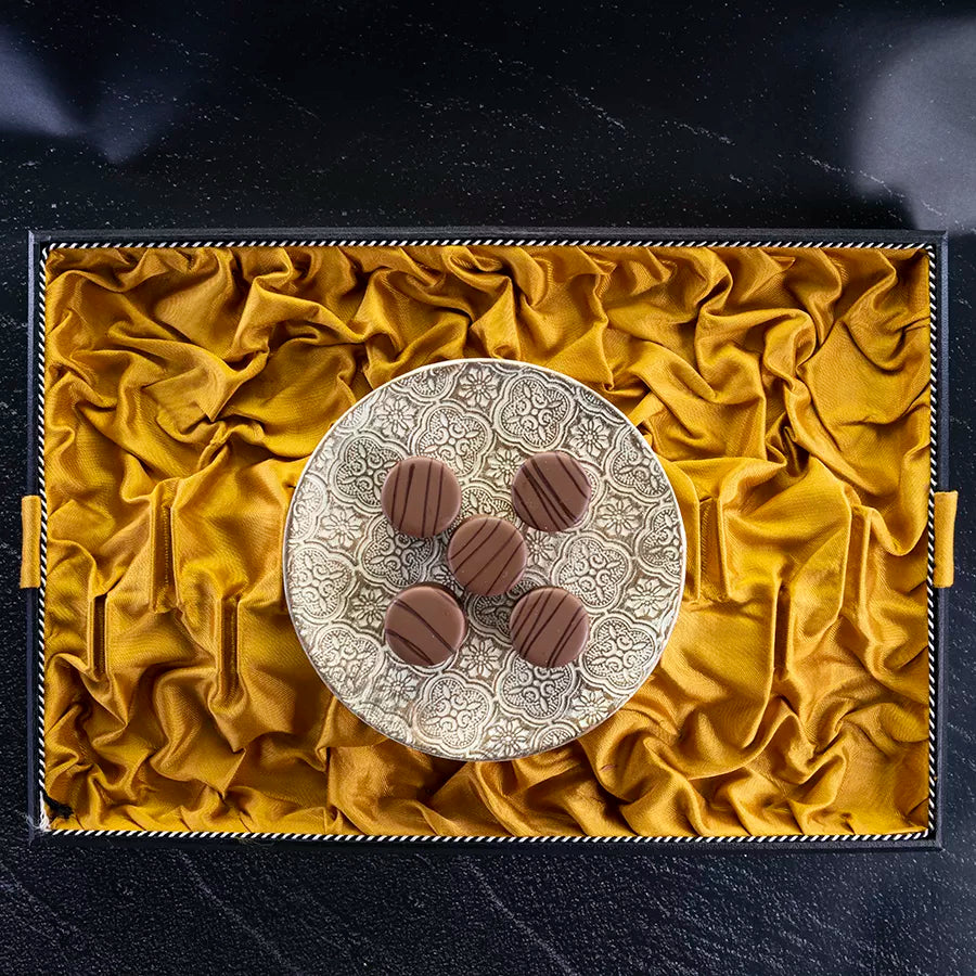 DORNAUERS Grand Cru Pralinen Sahne Karamell auf einem goldgemustertem Teller auf einem goldenem Tuch