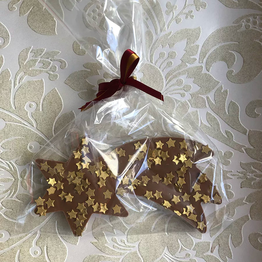 Dornauers Schokoladen Sternschnuppe Vollmilch mit goldenen Stern-Dekoren verpackt in transparenter Folie mit bordeauxroter Schleife