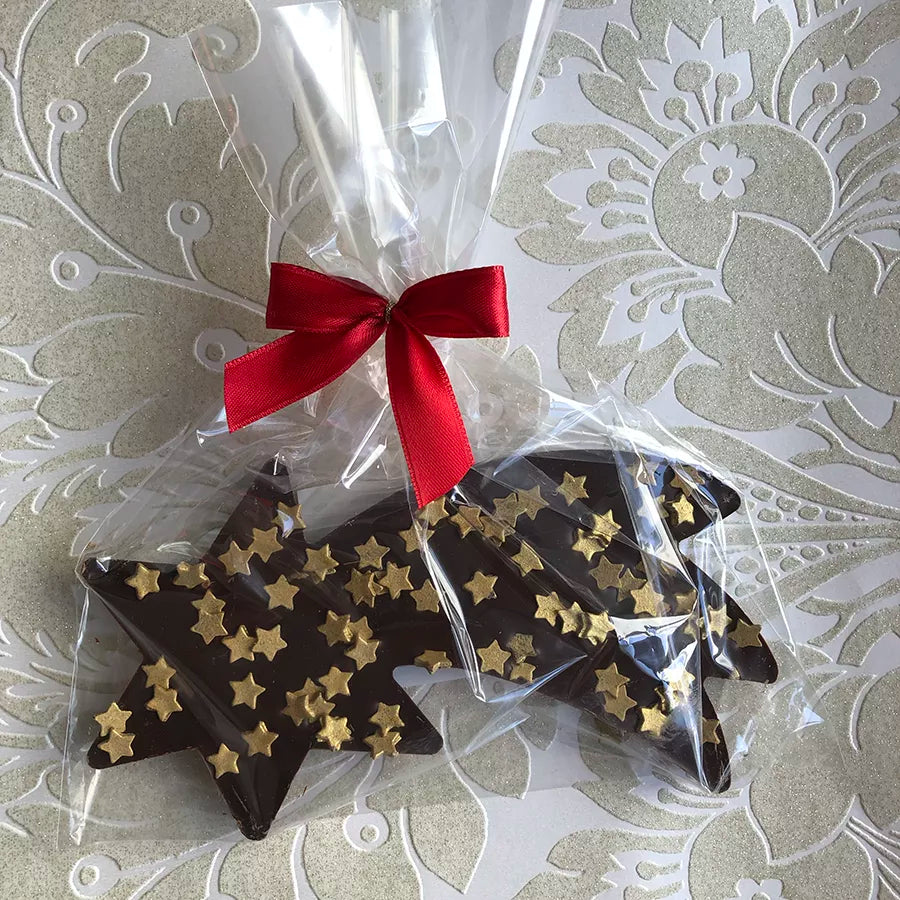 Dornauers Schokoladen Sternschnuppe Zartbitter mit goldenen Stern-Dekoren verpackt in transparenter Folie mit bordeauxroter Schleife